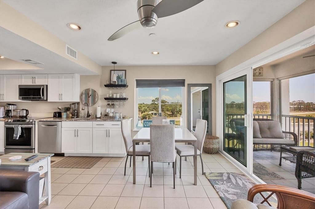 7070 Placida Road, Unit 1230 Placida, FL 33946 - Photo 25 of 60 a kitchen with stainless steel appliances granite countertop a stove top oven a sink dishwasher a dining table and chairs with wooden floor