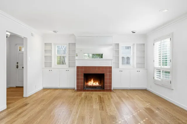 a view of an empty room with wooden floor fireplace and a window
