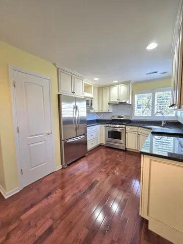 a kitchen with stainless steel appliances granite countertop hardwood floor sink stove and granite counter top