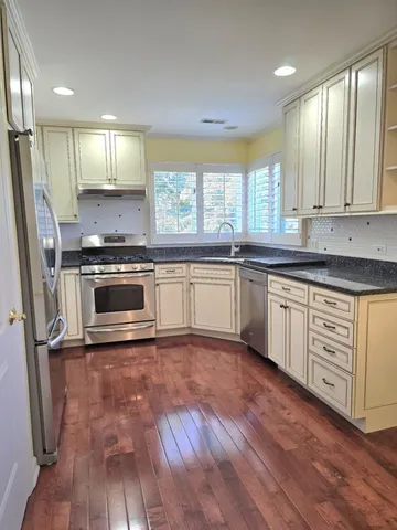 a kitchen with stainless steel appliances a stove a sink and white cabinets