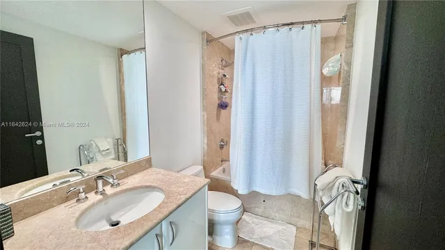 a bathroom with a sink a toilet and shower curtain
