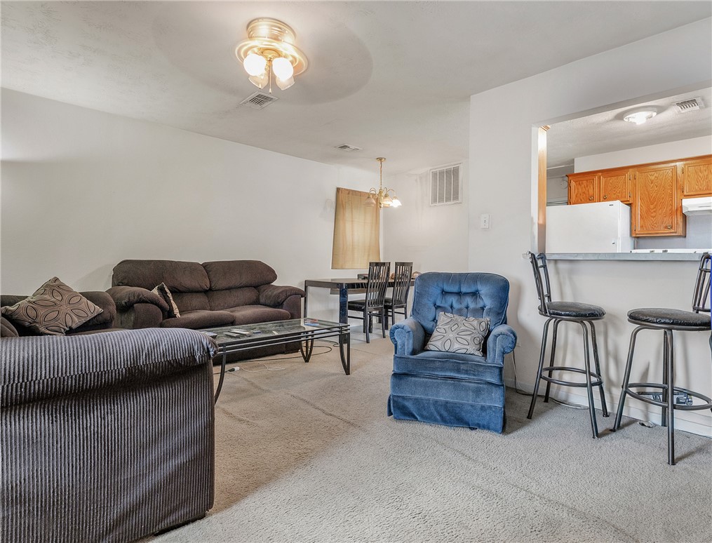 1003 West 17th Street Bryan, TX 77803 - Photo 2 of 6 Living area with light colored carpet and hanging lights