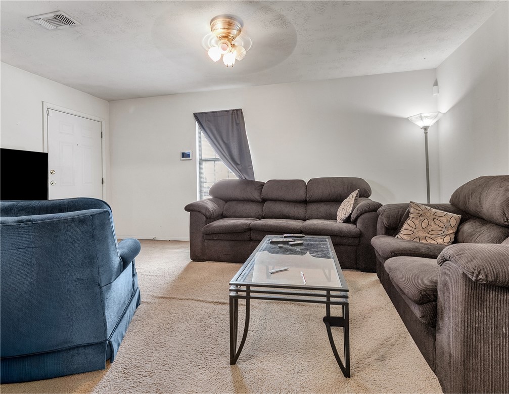 1003 West 17th Street Bryan, TX 77803 - Photo 3 of 6 Living area featuring carpet flooring, a ceiling fan, and a textured ceiling