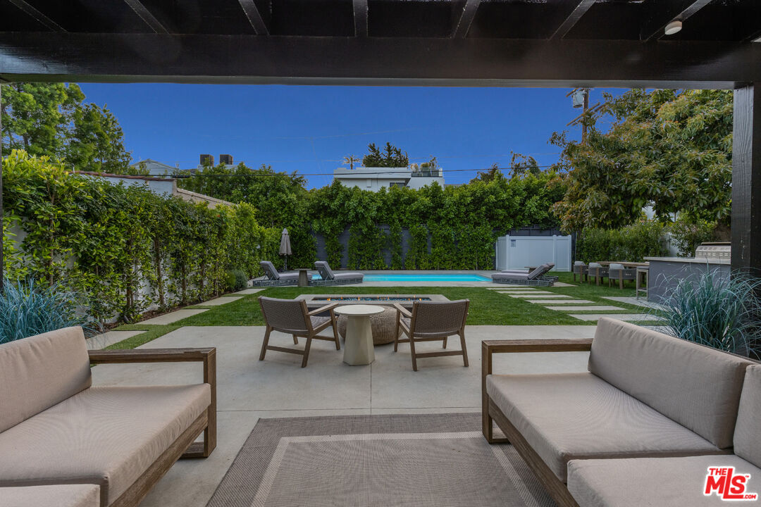 731 North Curson Avenue Los Angeles, CA 90046 - Photo 5 of 75 a view of a patio with couches table and chairs under an umbrella