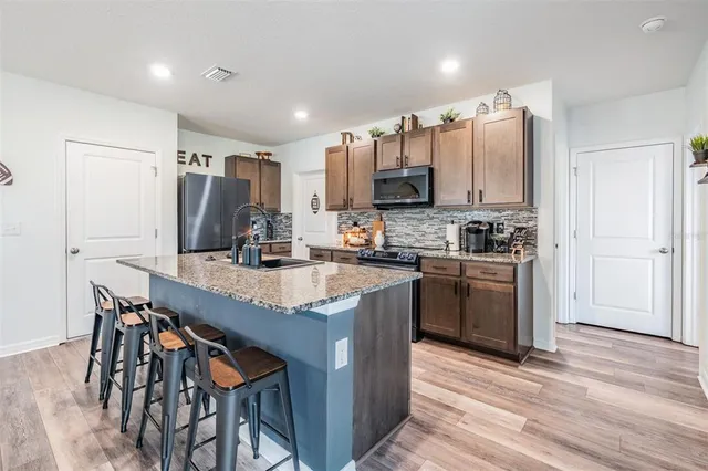 a kitchen with stainless steel appliances granite countertop a table chairs sink and cabinets
