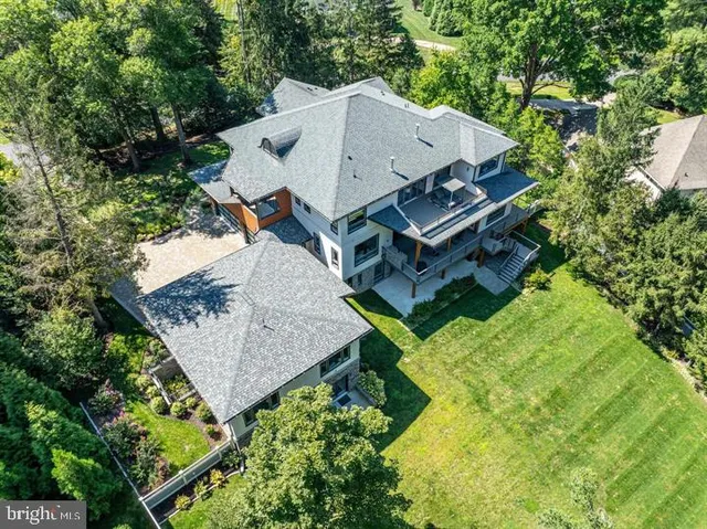 an aerial view of a house with a yard and trees all around