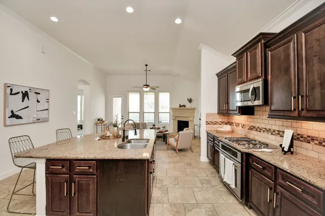 a kitchen with stainless steel appliances granite countertop a stove top oven a sink dishwasher a dining table and chairs