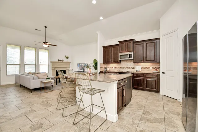 a kitchen with stainless steel appliances kitchen island granite countertop a stove a sink a microwave a dining table and chairs