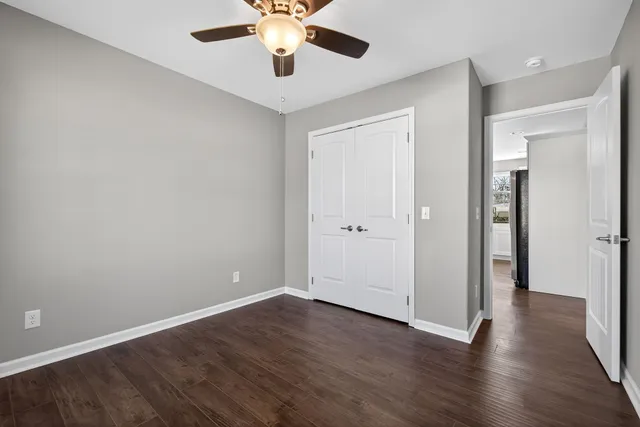 an empty room with wooden floor and a ceiling fan