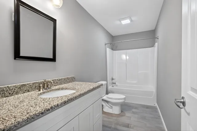 a bathroom with a granite countertop sink a toilet and a mirror