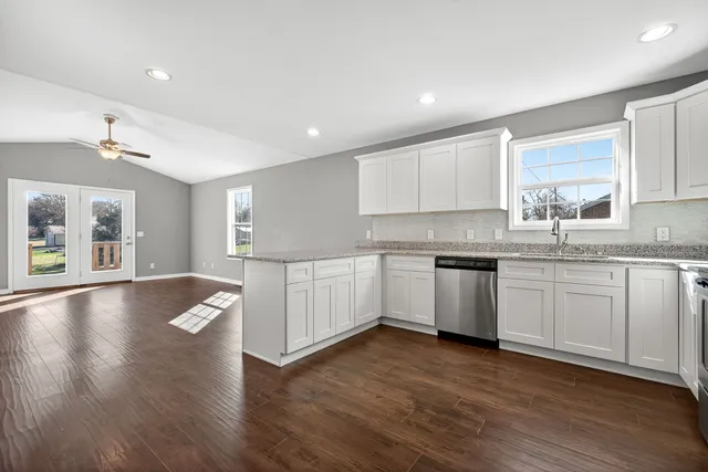 a kitchen with granite countertop a sink cabinets and wooden floor