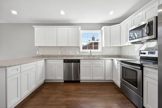 a kitchen with granite countertop white cabinets stainless steel appliances and a sink