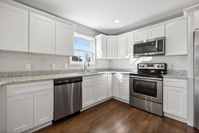 a kitchen with granite countertop a sink cabinets and stainless steel appliances