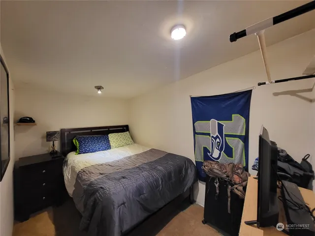 a bedroom with a bed and a flat tv screen on the dresser