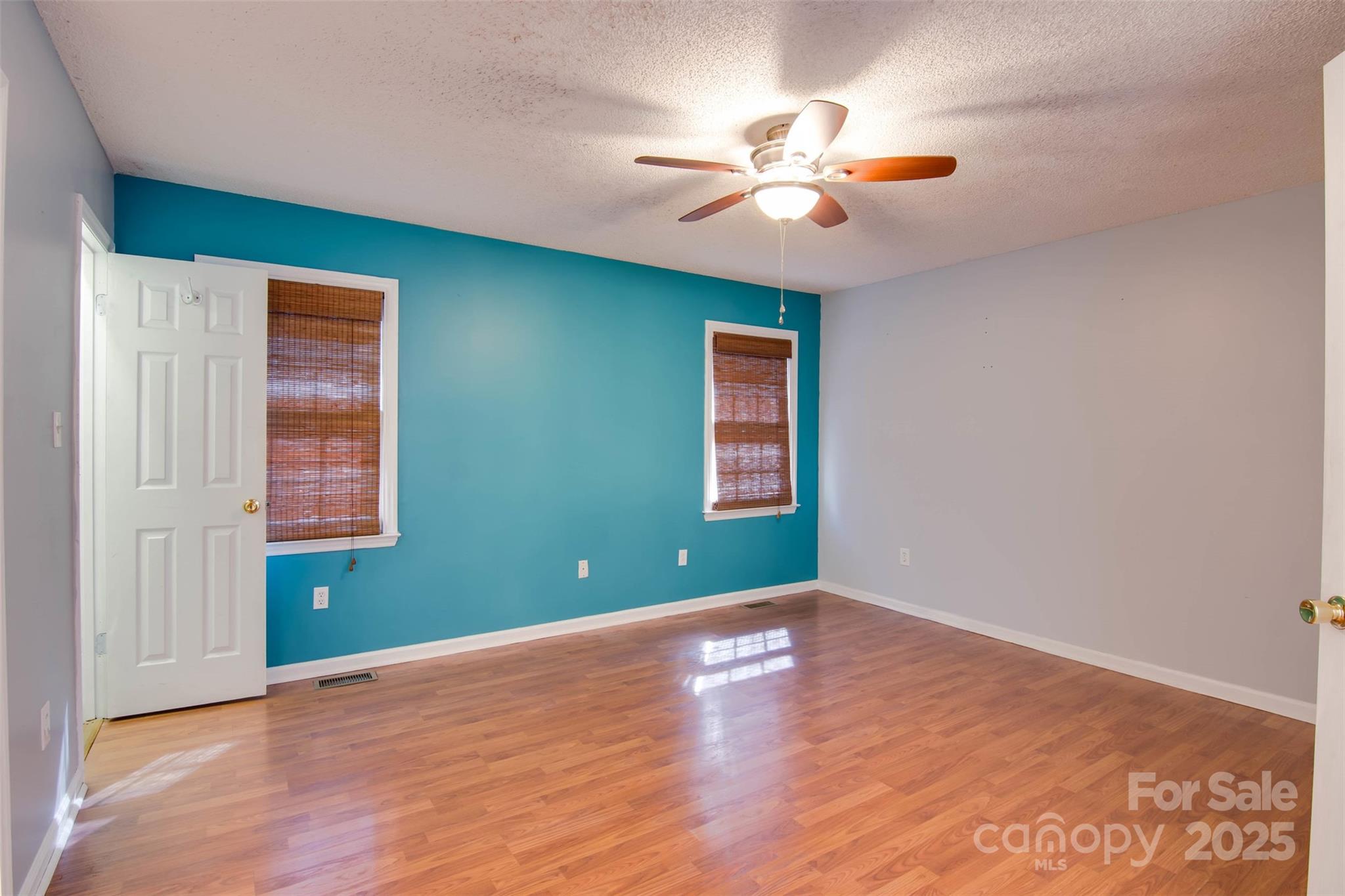 806 East Ridge Street Kings Mountain, NC 28086 - Photo 20 of 38 an empty room with wooden floor chandelier fan and windows