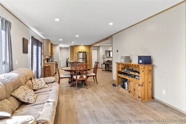a living room with furniture and a dining table with wooden floor