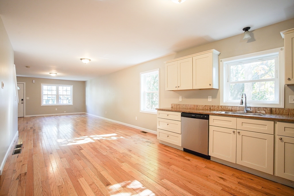 18-20 Healey Street, Unit 20 Springfield, MA 01151 - Photo 5 of 14 a kitchen with granite countertop a stove a sink and white cabinets with wooden floor