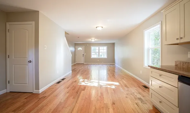 a view of empty room with wooden floor and fan