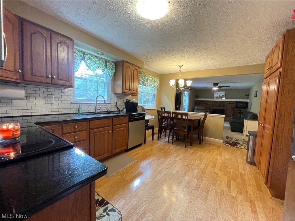 Kitchen with dishwasher, sink, ceiling fan with chandelier, and light floors