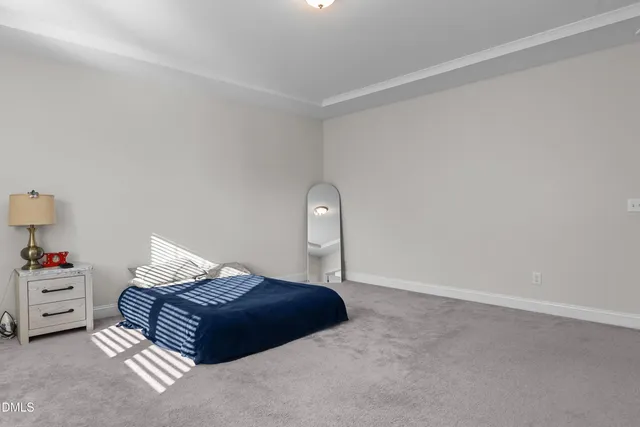 a spacious bedroom with a bed and a lamp on a dresser