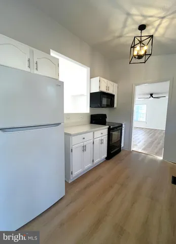 a kitchen with stainless steel appliances granite countertop a stove a sink dishwasher and white cabinets with wooden floor