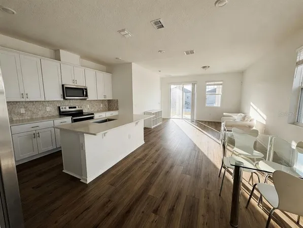 a kitchen with granite countertop wooden floors white cabinets and stainless steel appliances