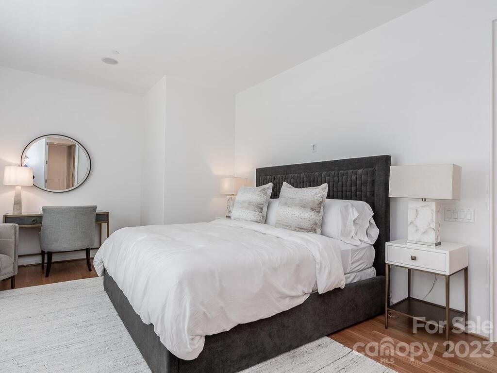 1333 Queens Road, Unit E1 Charlotte, NC 28207 - Photo 12 of 19 a bedroom with a bed a mirror and lamp on desk