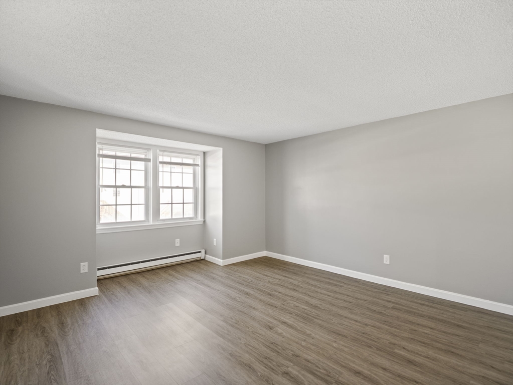 1821 Middlesex Street, Unit 10 Lowell, MA 01851 - Photo 11 of 26 a view of an empty room with wooden floor and a window
