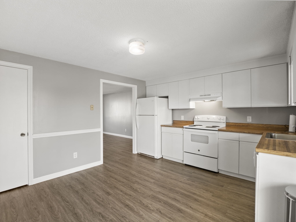 1821 Middlesex Street, Unit 10 Lowell, MA 01851 - Photo 2 of 26 a kitchen with a refrigerator and white cabinets