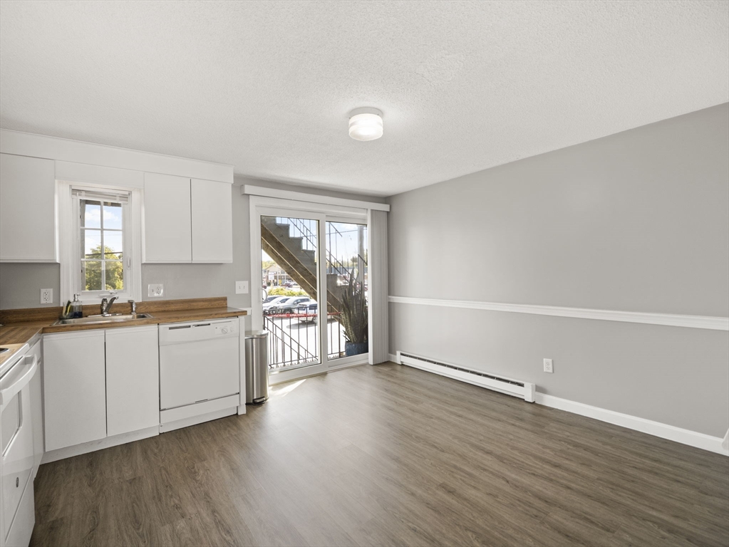 1821 Middlesex Street, Unit 10 Lowell, MA 01851 - Photo 4 of 26 a large white kitchen with wooden floors and white walls