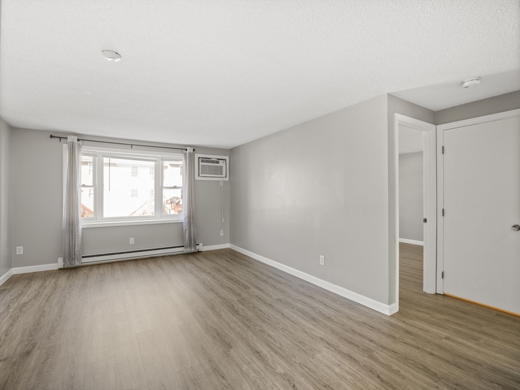 1821 Middlesex Street, Unit 10 Lowell, MA 01851 - Photo 7 of 26 a view of an empty room with wooden floor and a window