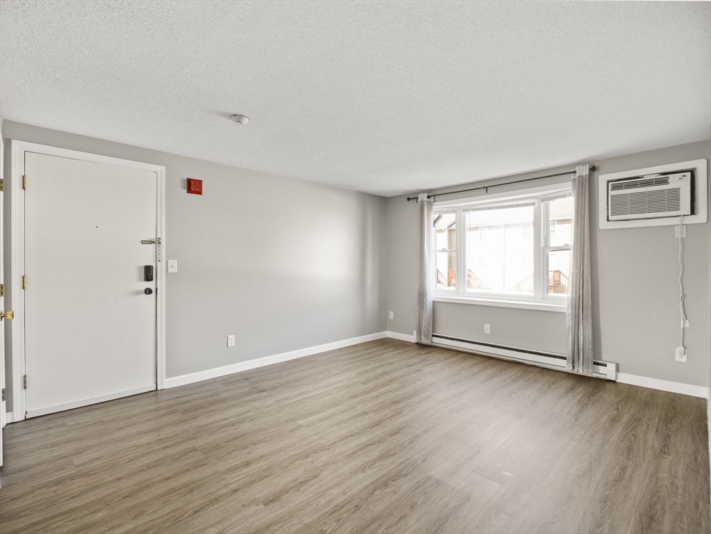 1821 Middlesex Street, Unit 10 Lowell, MA 01851 - Photo 10 of 26 an empty room with wooden floor and windows