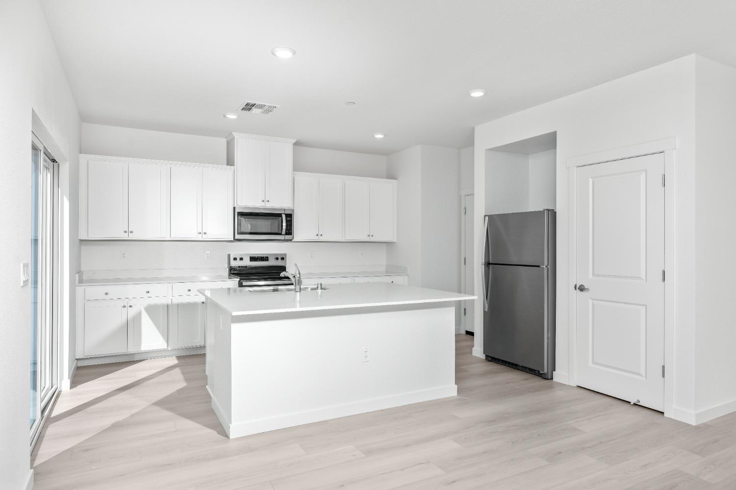 929 South Mylea Court Stockton, CA 95215 - Photo 7 of 8 a kitchen with a refrigerator a stove top oven and white cabinets