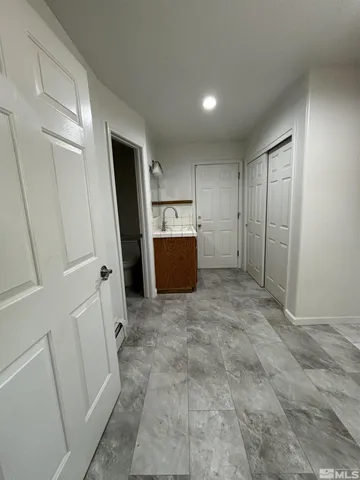a view of hallway with refrigerator and white cabinets