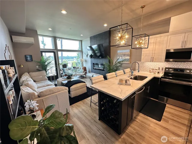 a living room with stainless steel appliances kitchen island granite countertop a stove a sink dishwasher and a dining table with the living room view