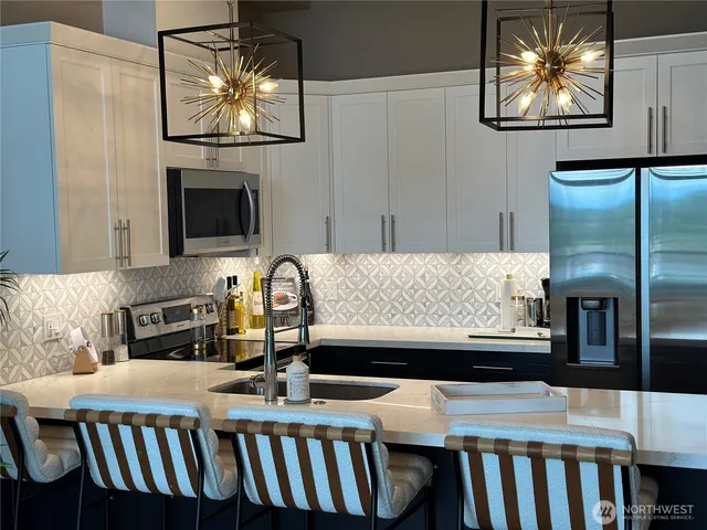a kitchen with stainless steel appliances granite countertop a stove top oven a sink and a refrigerator