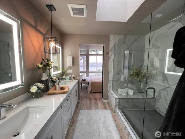 a spacious bathroom with a double vanity sink a mirror a bathtub and next to a window