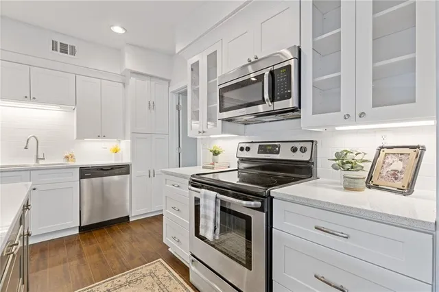a kitchen with cabinets stainless steel appliances and wooden floor
