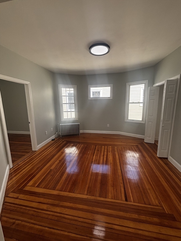 33 Wolcott Street, Unit 3 Boston, MA 02121 - Photo 2 of 8 an empty room with wooden floor and windows