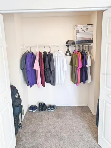 a view of walk in closet with clothes and shoes