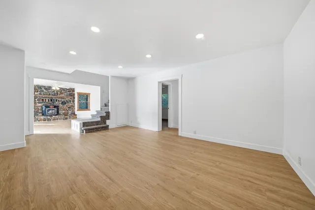 a view of an empty room with a window and wooden floor