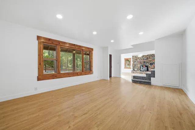 a view of an empty room with window and wooden floor