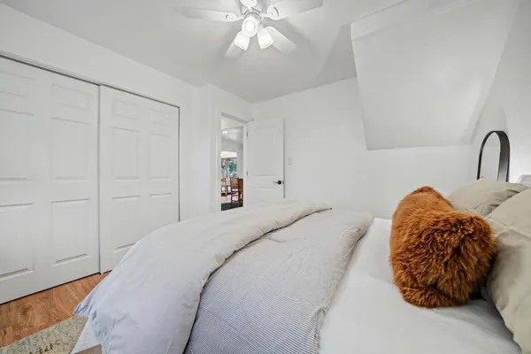 an empty room with wooden floor ceiling fan and windows