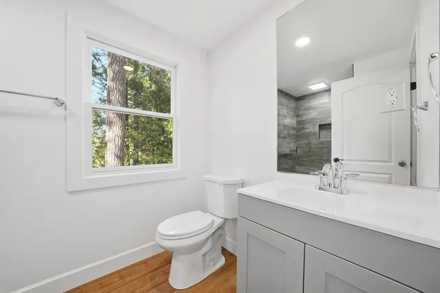 an empty room with wooden floor ceiling fan and windows