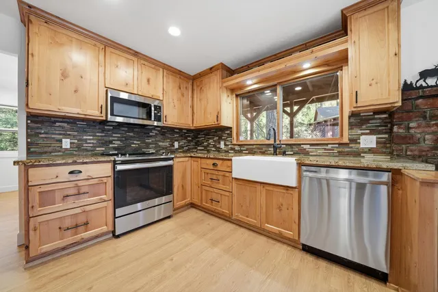 an empty room with wooden floor cabinet and windows