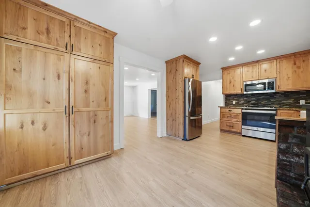 a view of a hallway with wooden floor and a bathroom