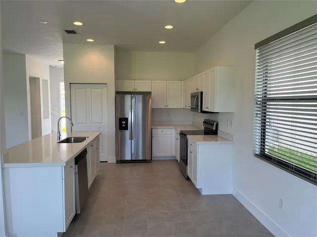 a kitchen with stainless steel appliances granite countertop a refrigerator a stove and a sink