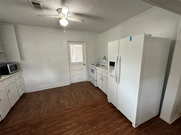 a kitchen with granite countertop a refrigerator and a stove top oven