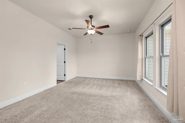 an empty room with fan and windows