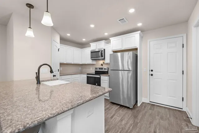 a kitchen with kitchen island granite countertop stainless steel appliances a refrigerator a sink a center island and cabinets